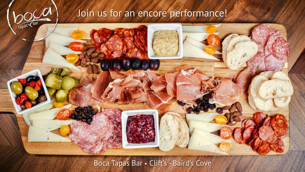 The Boca Tapas and Bar ad. A wooden table with a wooden charcuterie board with various meats, cheeses, bread, and vegetables. At the top of the ad in white it says Join us for an encore performance! At the bottom of the ad it says Bocas Tapas Bar. Clift's -Baird's Cove.